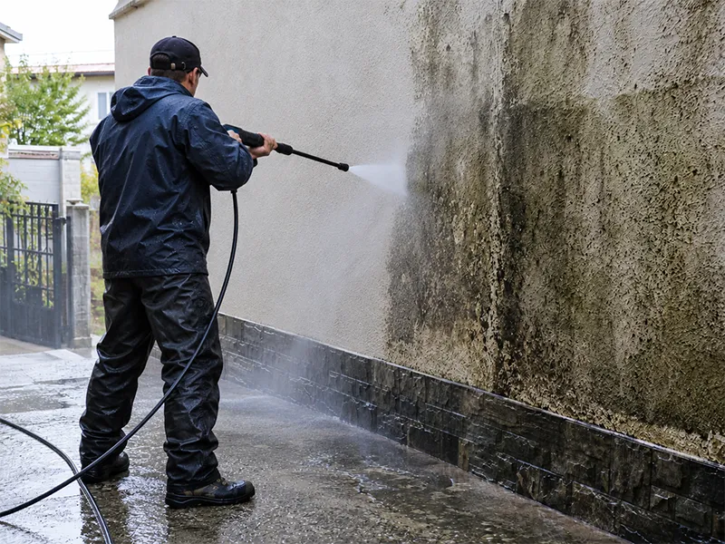 man pressure cleaning wall